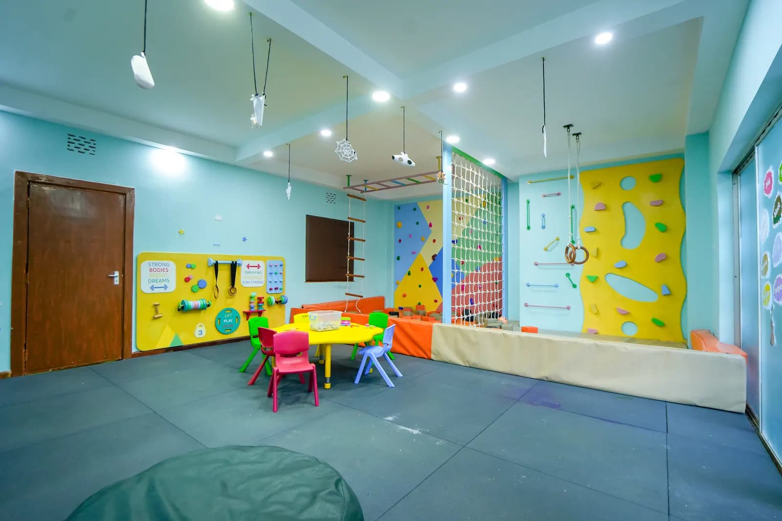 A bright activity room at Daydreams with low tables, floor cushions and a climbing wall