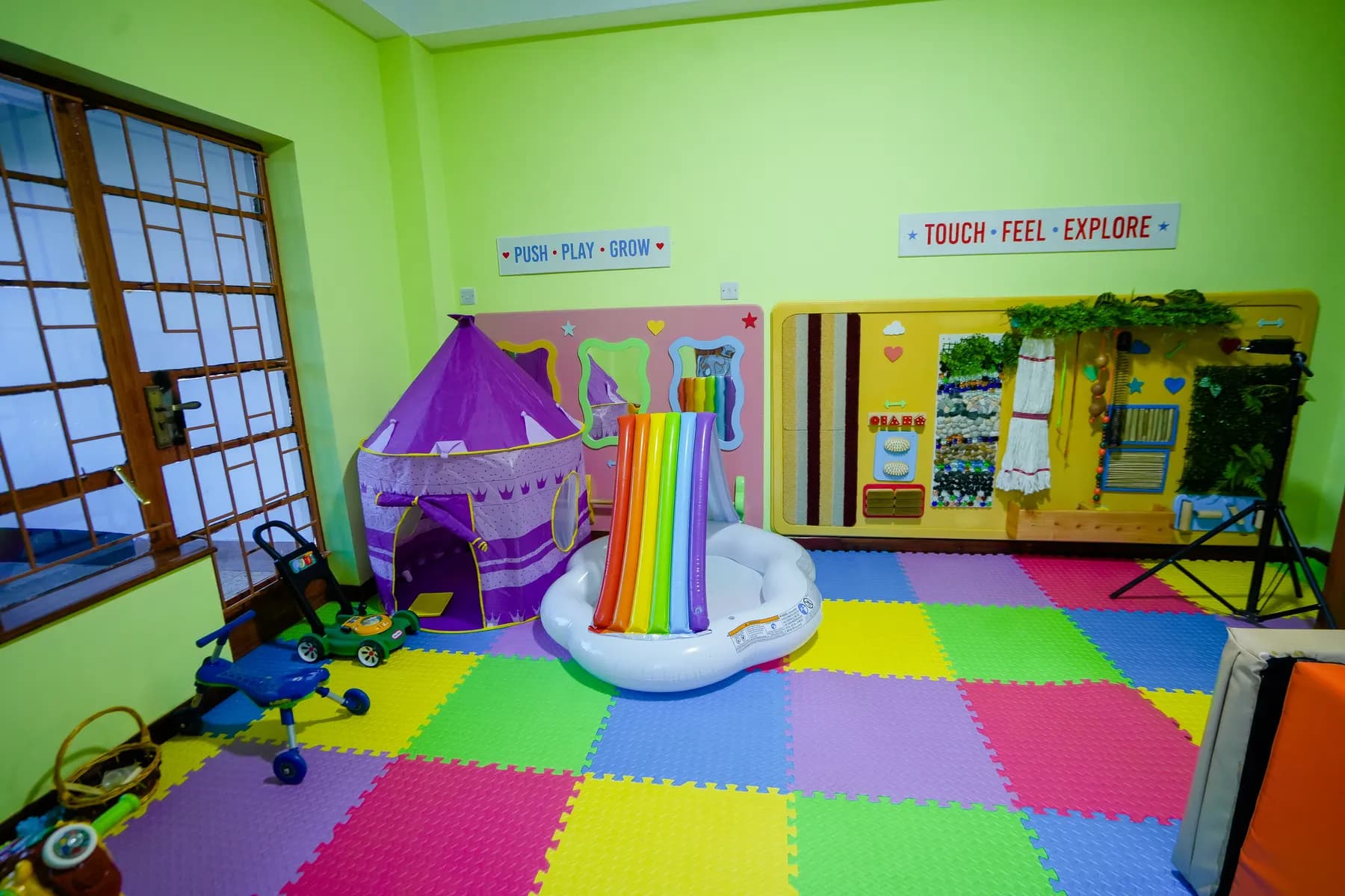 Soft play room with a play tent, rainbow slide and sensory wall